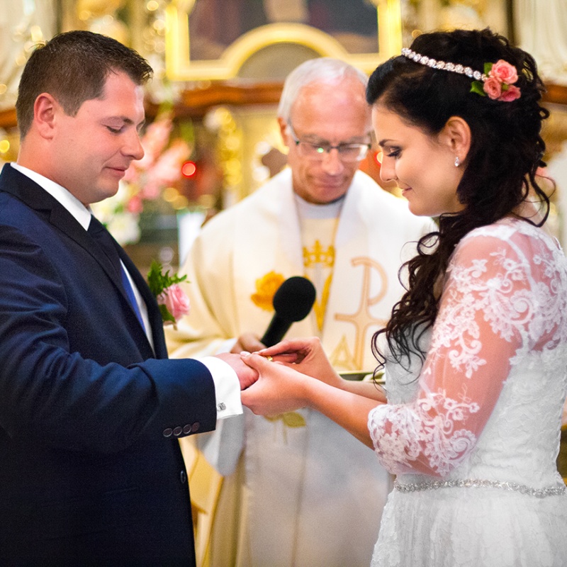Panna młoda zakłada obrączkę swojemu nowo poślubionemu mężowi na palec